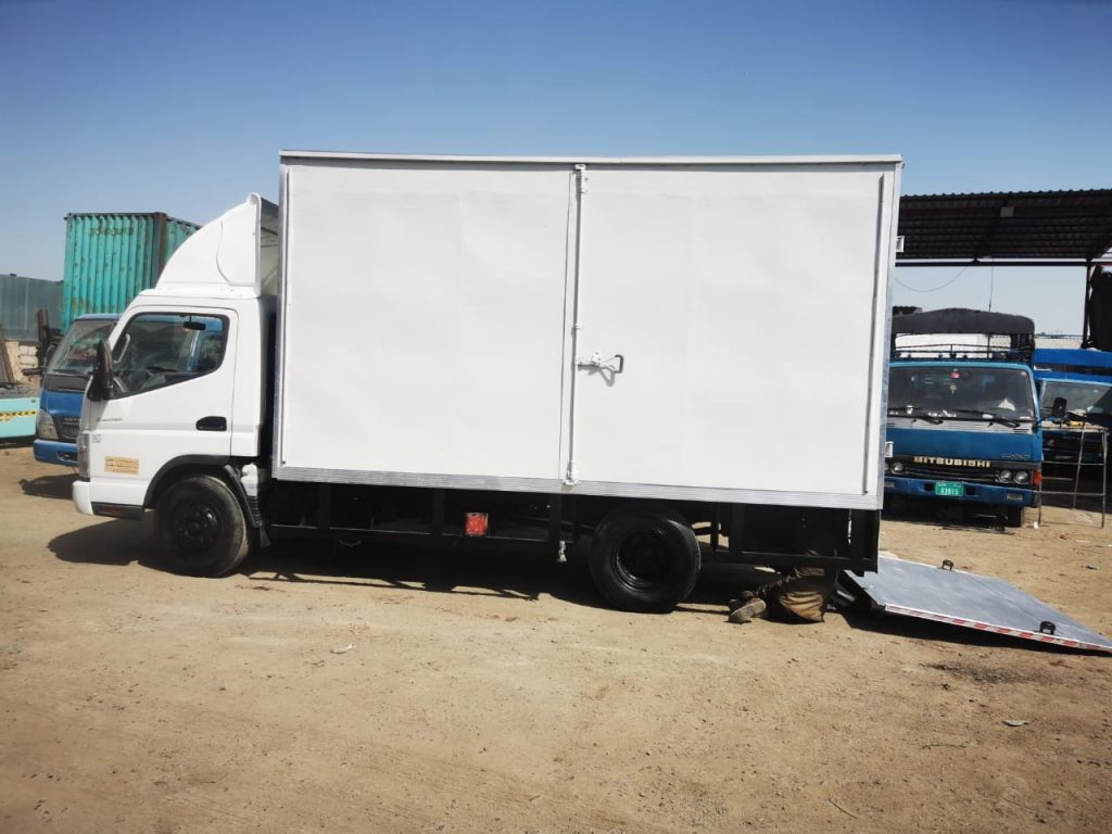 A 3-ton white pickup truck parked near a warehouse in Dubai, ready for cargo transport